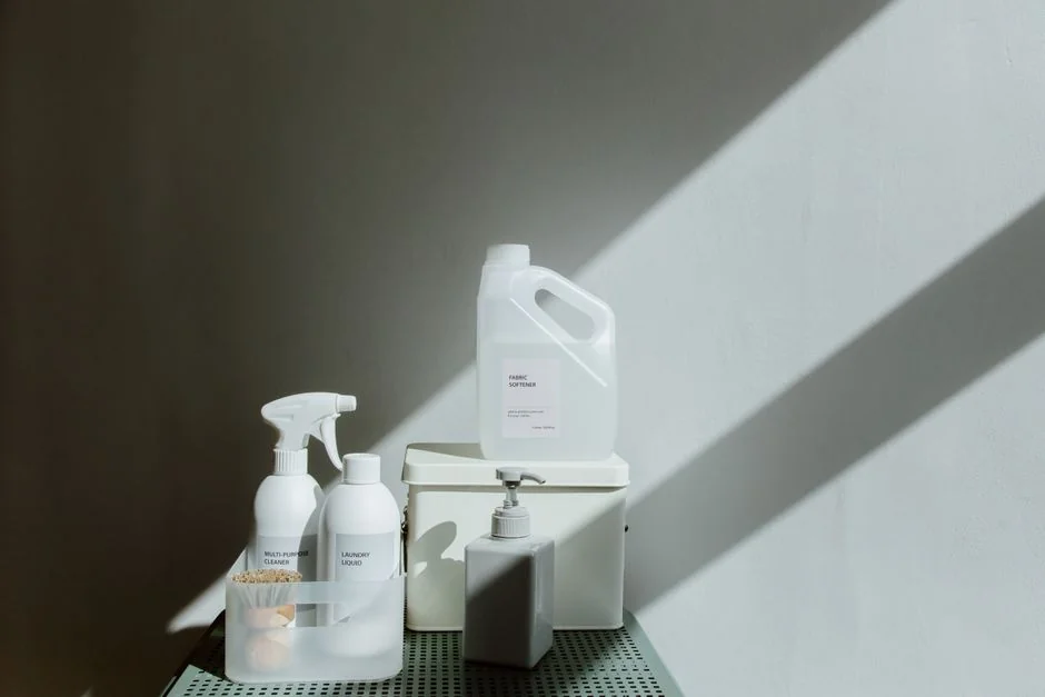 A detailed view of a hand cleaning a stovetop using a spray bottle and cloth.